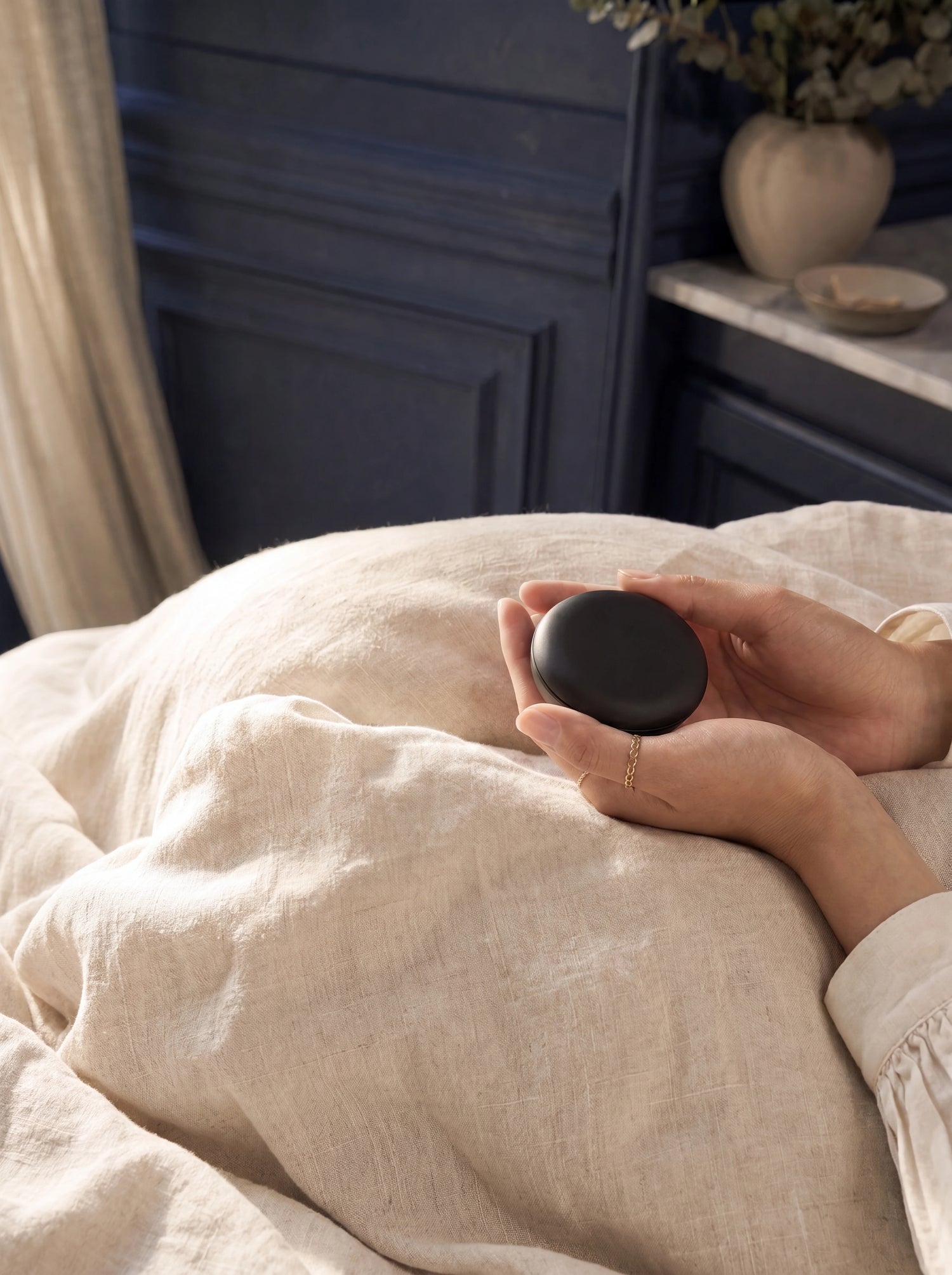 Garantie 100 nuits SOR — mains tenant le boîtier Sleepyzy sur drap lin